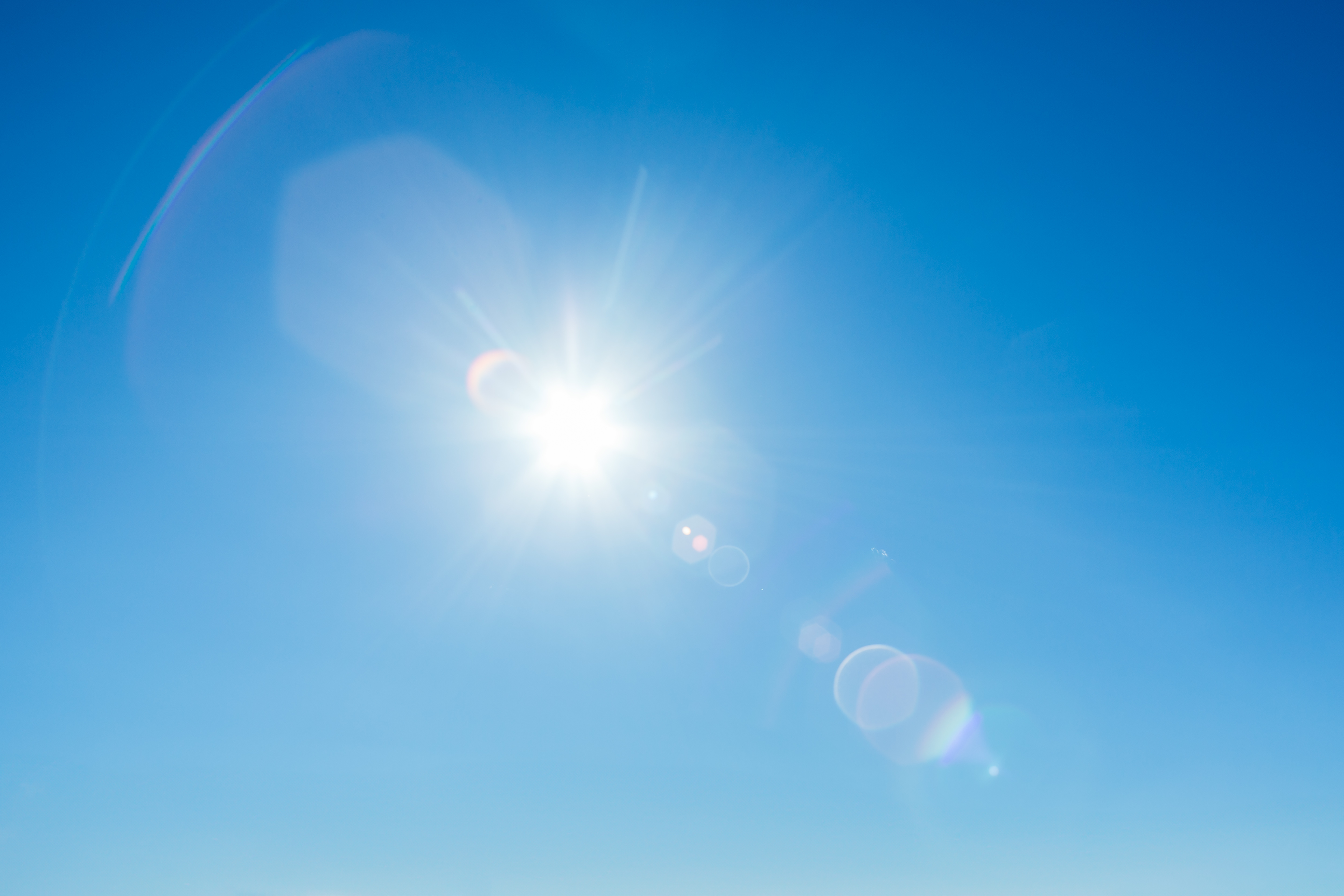 青空に輝く太陽、映り込むフレア